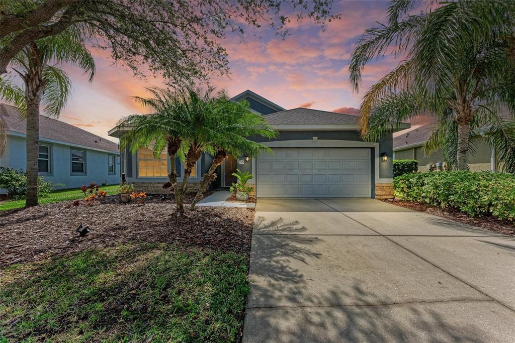 a view of a house with a yard and palm trees