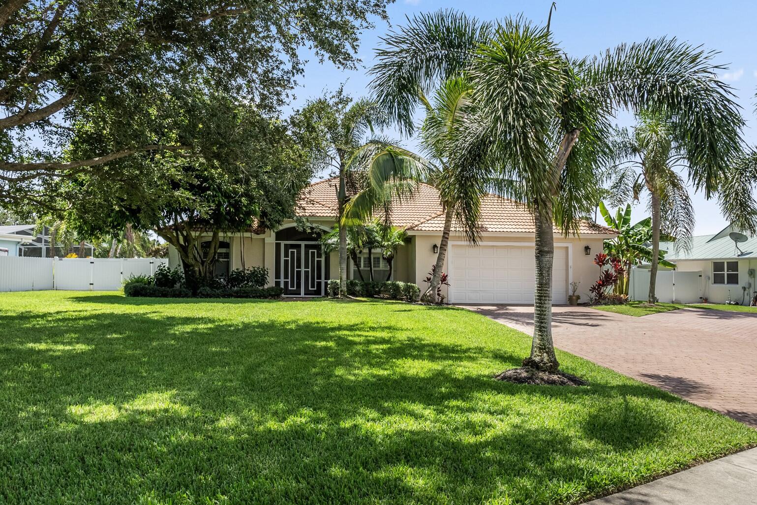 a backyard of a house with table and chairs plants and palm trees