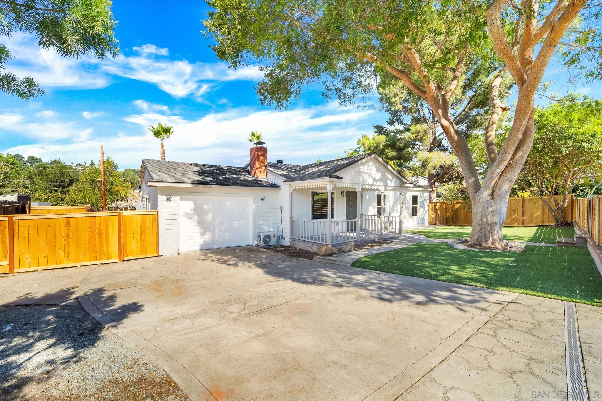 a view of a house with a yard and a large tree