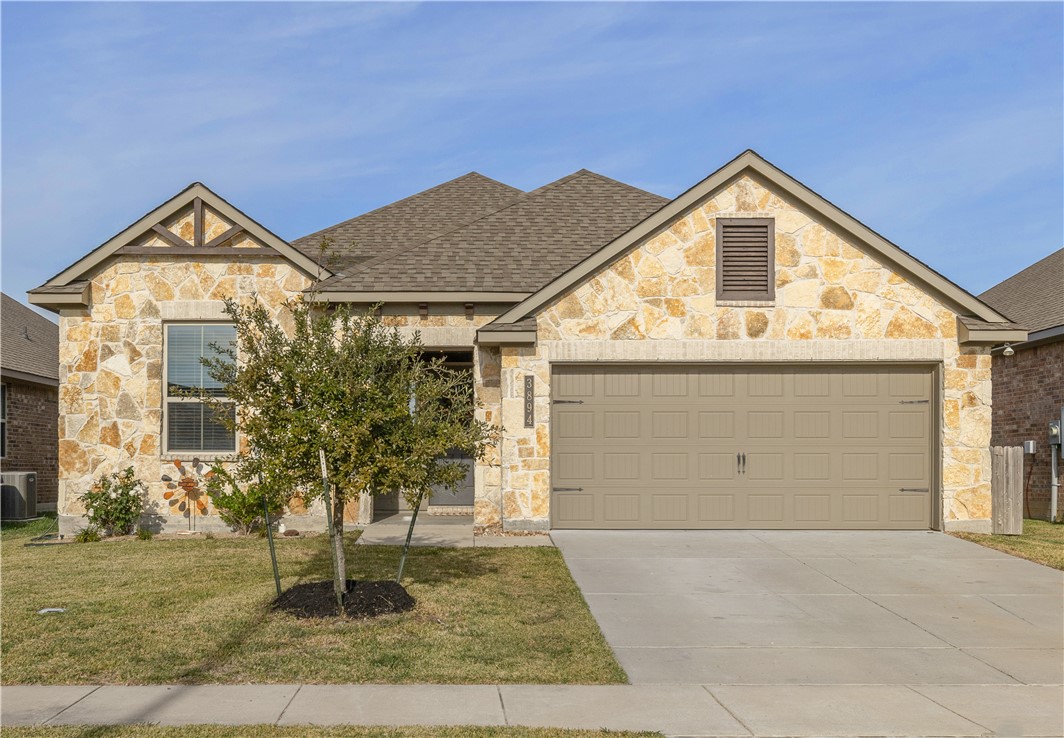 View of front facade with cooling unit, a garage,