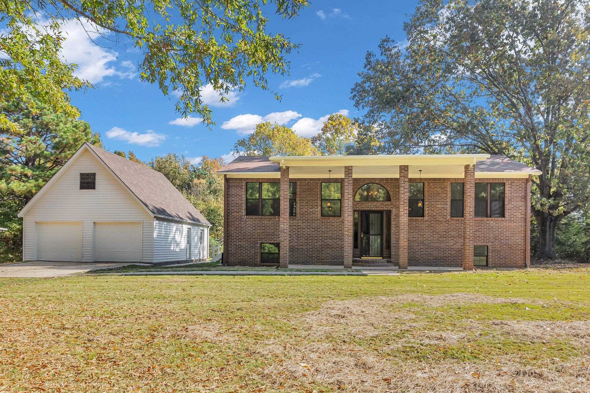 Raised ranch featuring a front yard, an outbuilding, and a garage