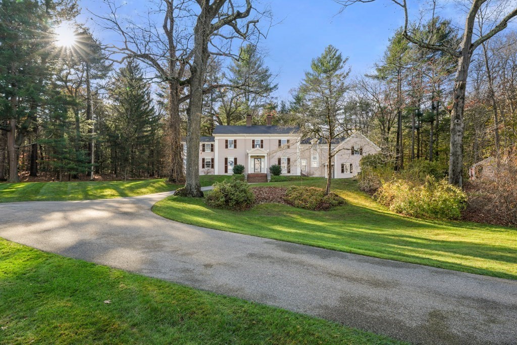 a view of a house with a big yard and potted plants and large trees