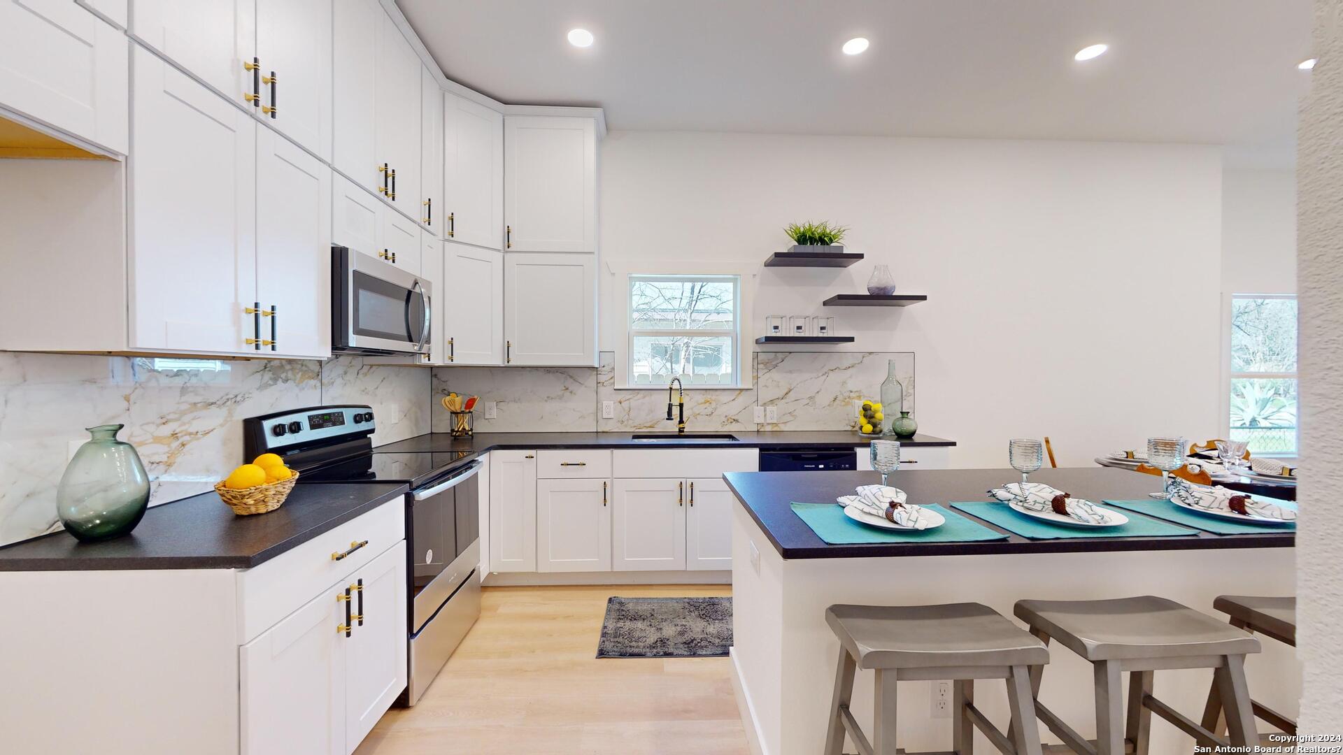 a kitchen with a sink a stove cabinets and dining table