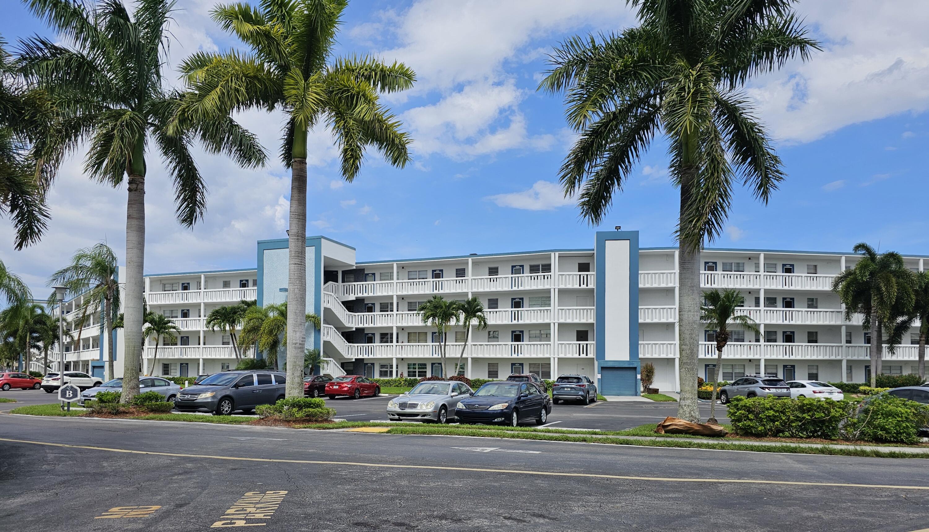 a front view of multi story residential apartment building with yard and traffic signal