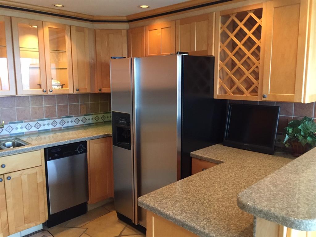 a kitchen with stainless steel appliances granite countertop a refrigerator and a sink