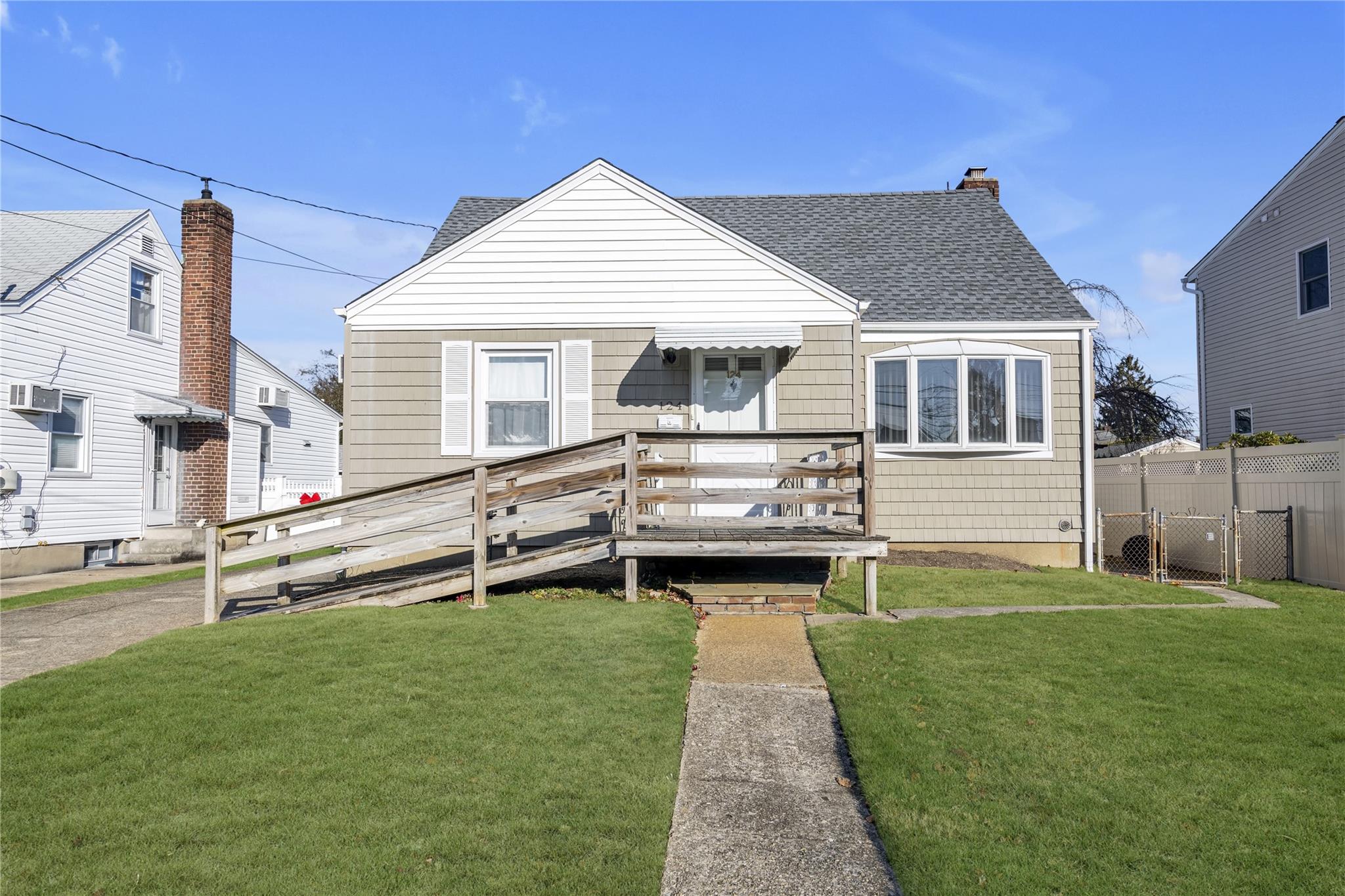 View of front of property featuring a front yard, an AC wall unit, and a wooden deck