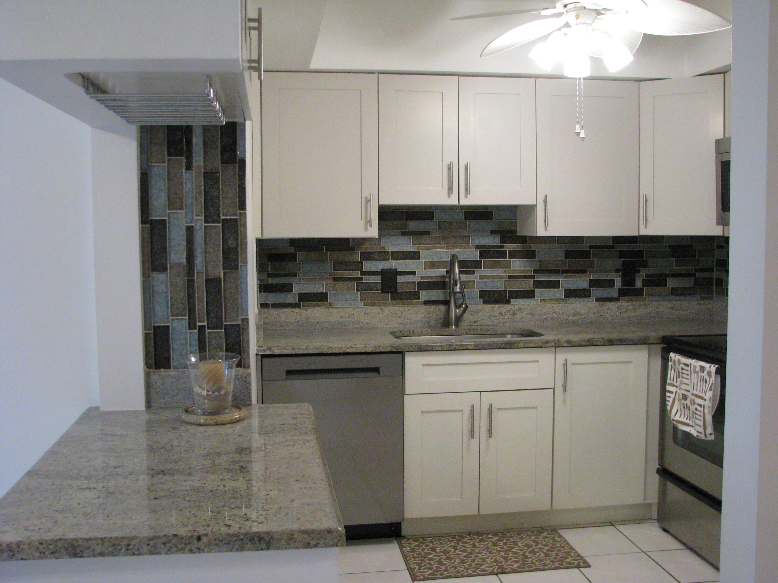 a kitchen with stainless steel appliances granite countertop a stove a sink and a white cabinets