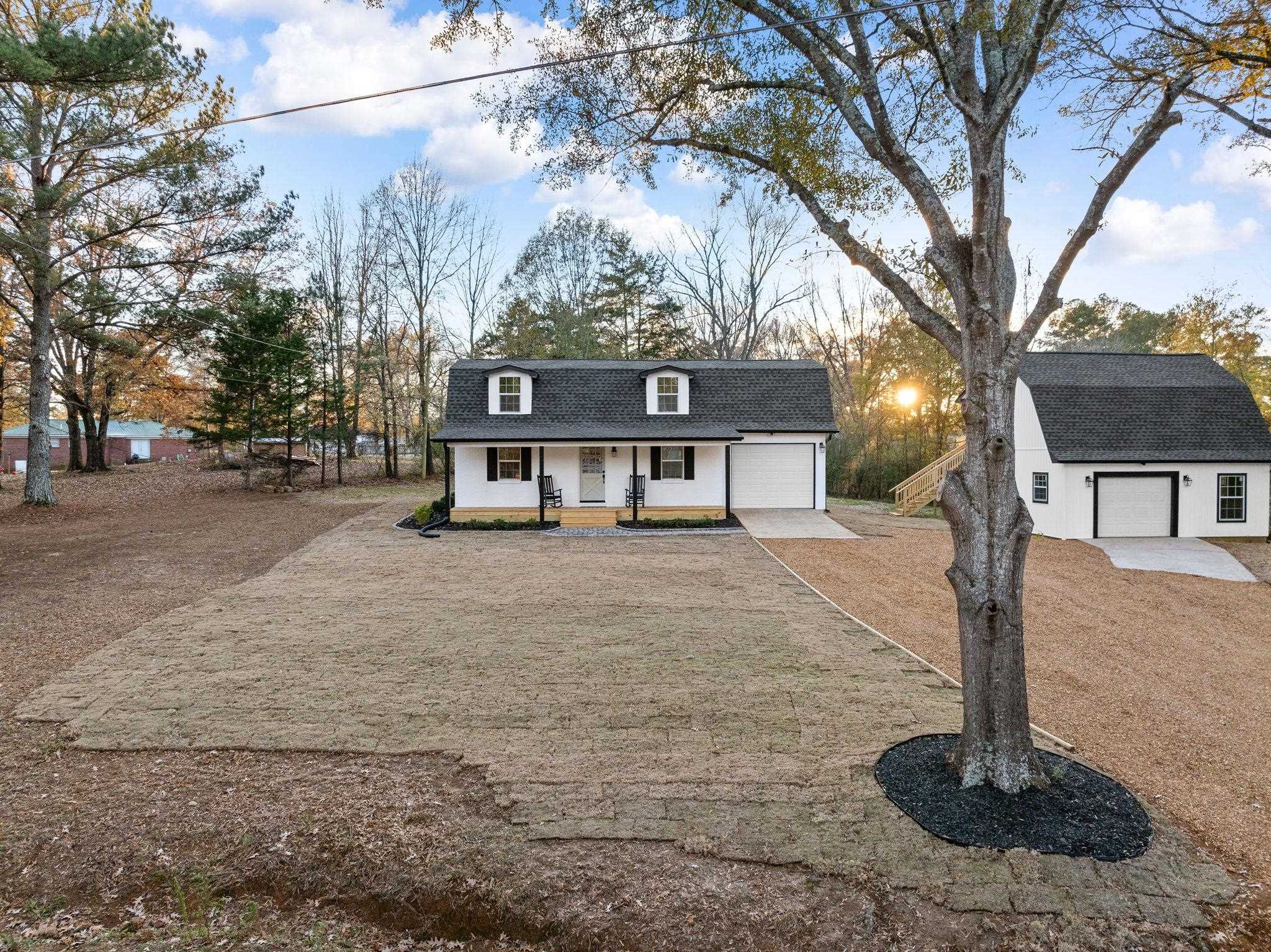 View of front of home with a porch, an outdoor structure, and a front lawn