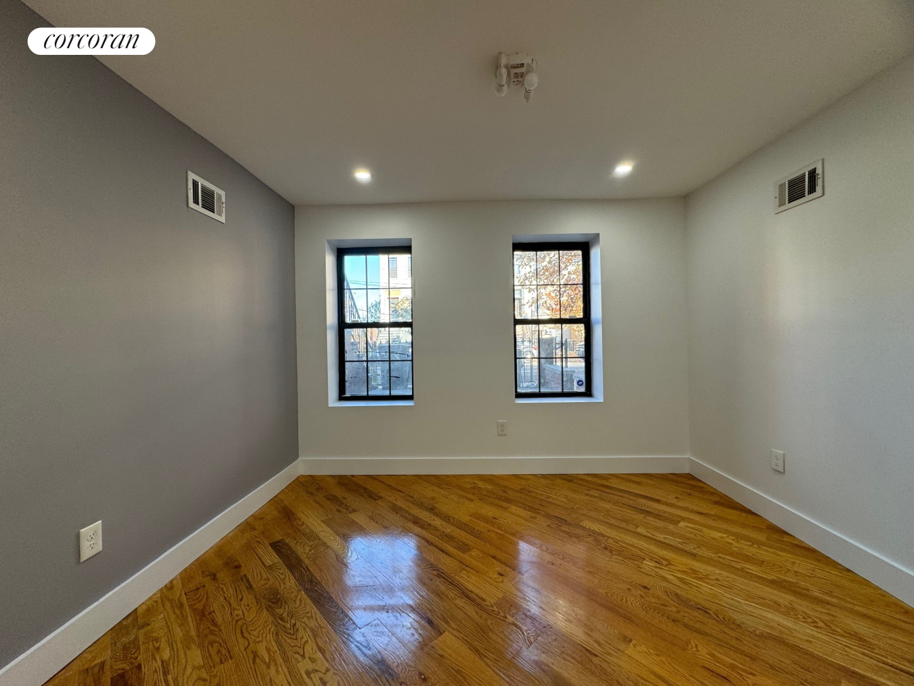 a view of empty room with wooden floor and fan