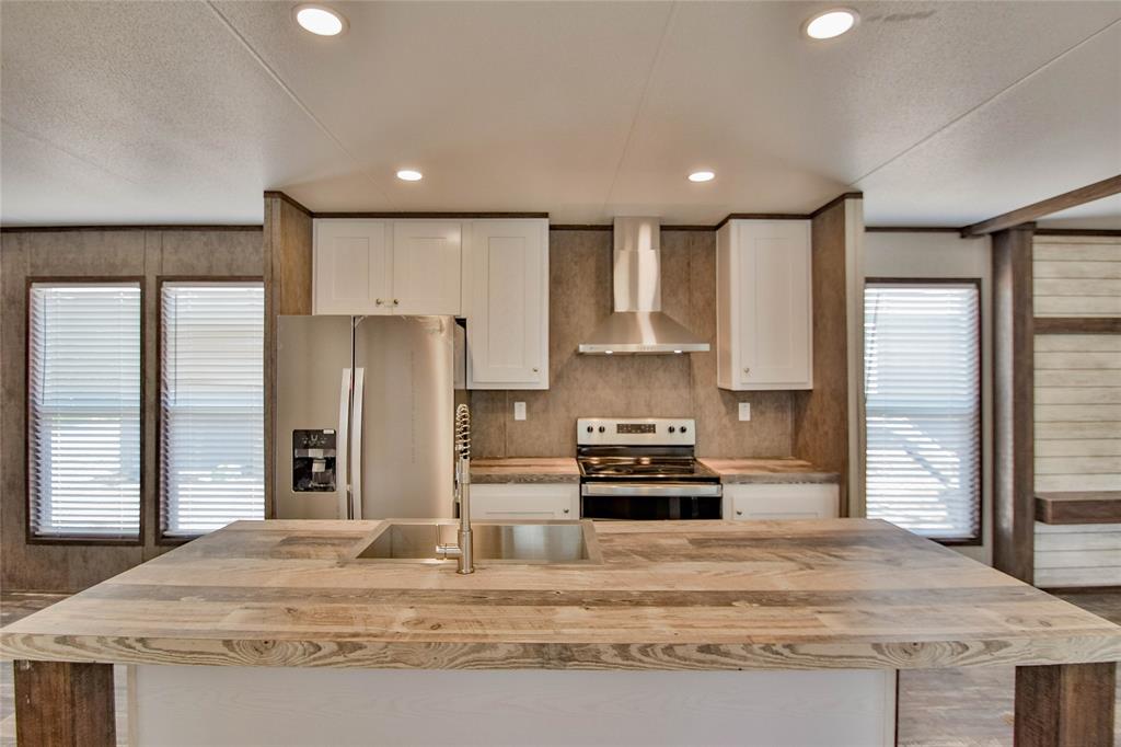 a kitchen with stainless steel appliances granite countertop a refrigerator a stove and a sink