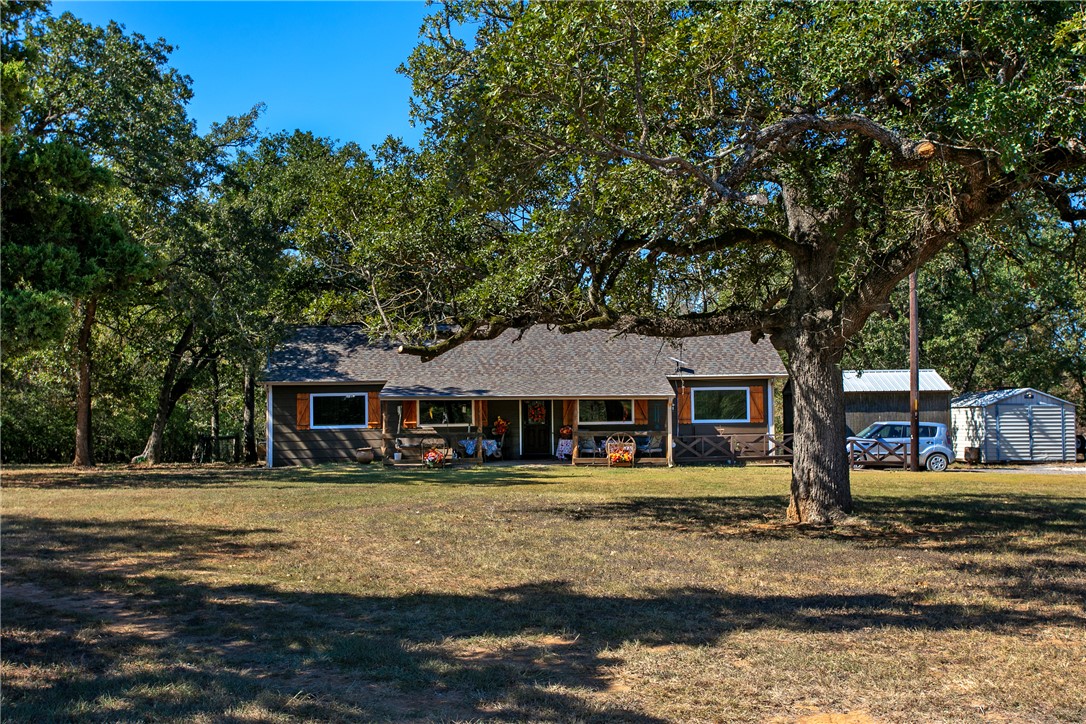 a front view of a house with garden and trees