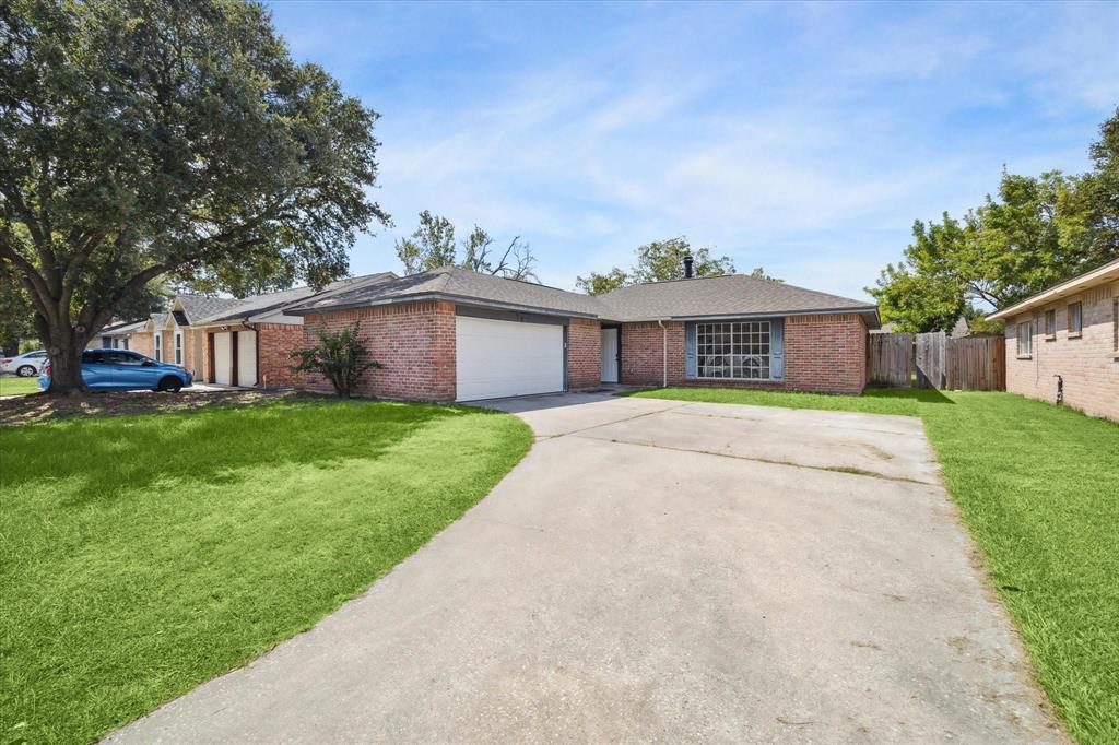 a view of house with a big yard and large trees