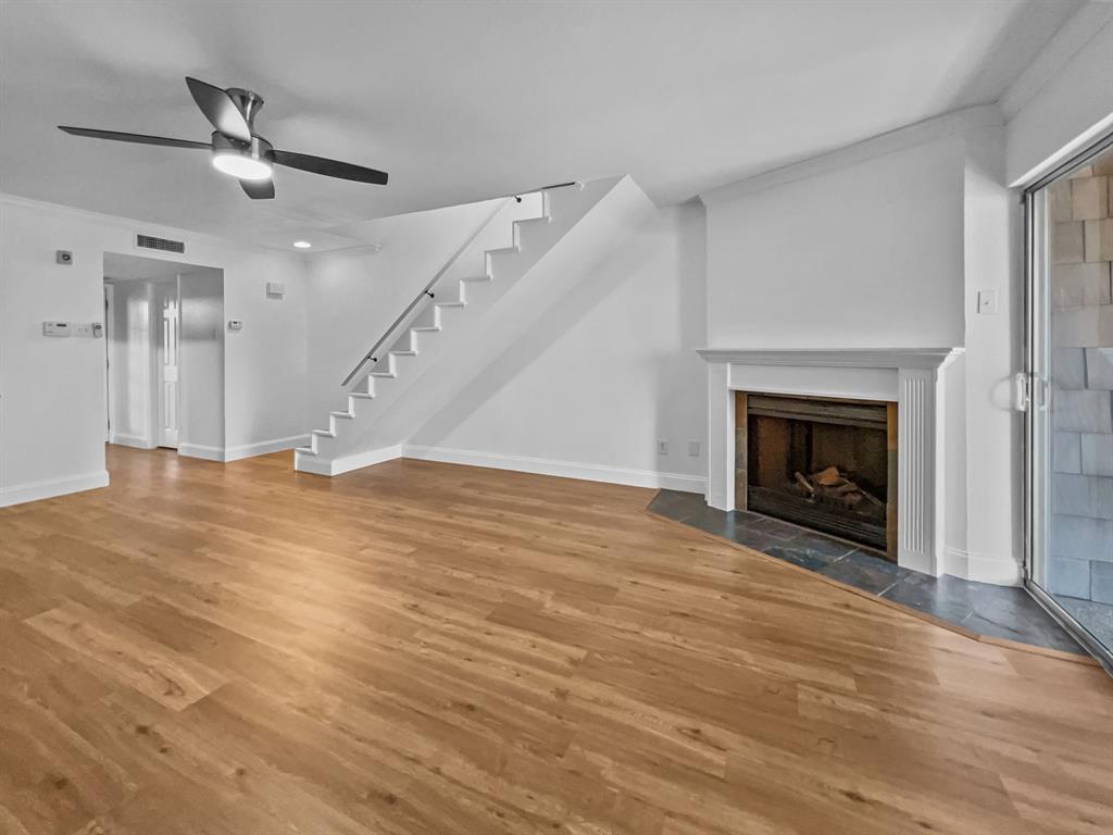 a view of an empty room with wooden floor a fireplace