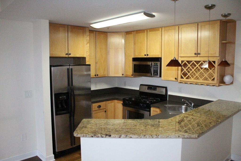 a kitchen with granite countertop kitchen island stainless steel appliances a refrigerator sink and microwave