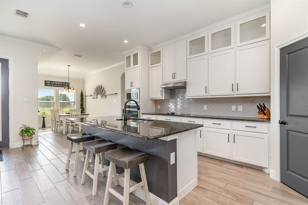 a kitchen with stainless steel appliances granite countertop a sink a stove a dining table and chairs