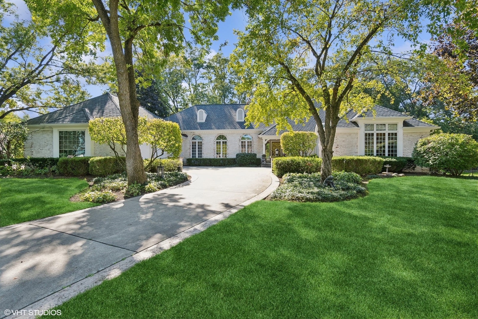 a front view of a house with a garden and trees