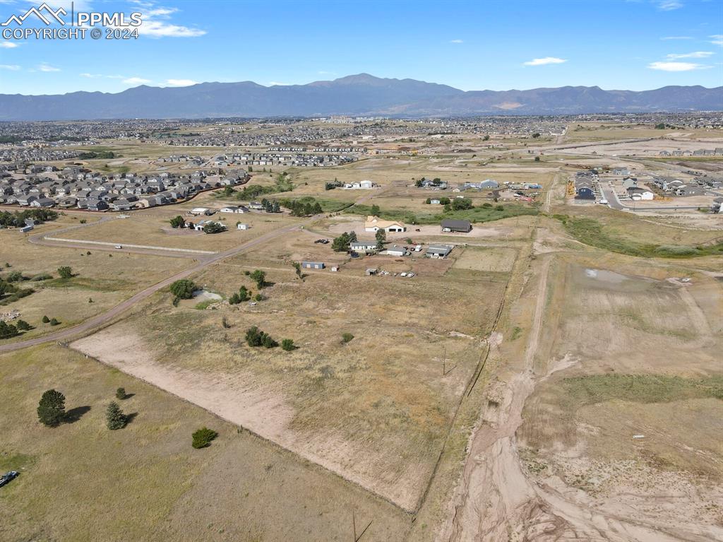 Aerial view towards the mountains and Colorado Springs, road Mustang Pl is to the left, open space to the right.