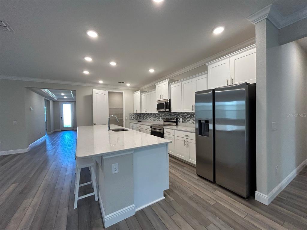 a kitchen with kitchen island white cabinets and stainless steel appliances