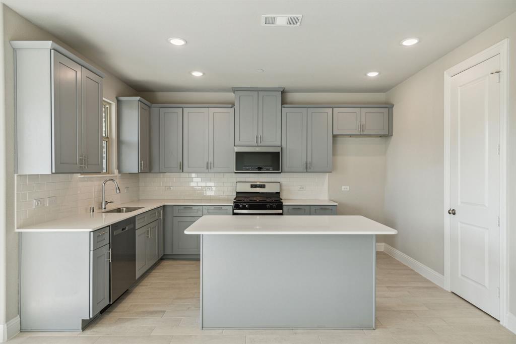 a kitchen with sink a microwave and cabinets