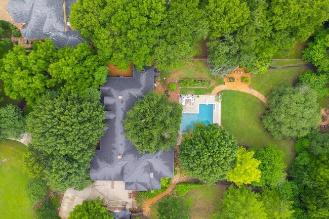 an aerial view of a house with a yard and trees all around