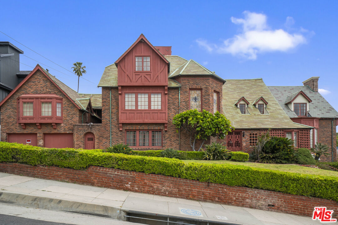 a view of a brick house next to a yard with big trees