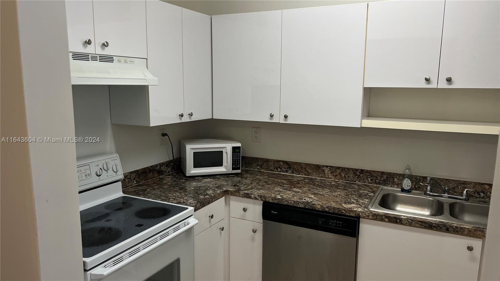 a kitchen with granite countertop white cabinets and a stove top oven