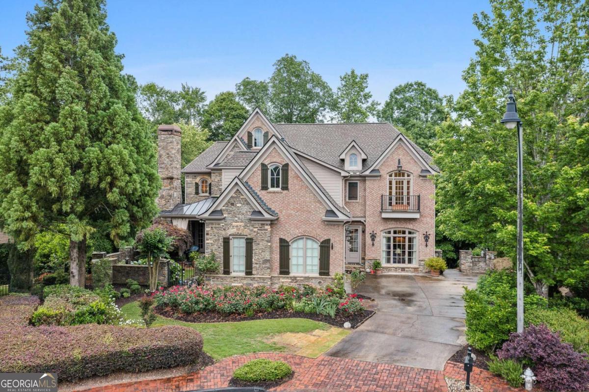 a view of a white house next to a yard with big trees