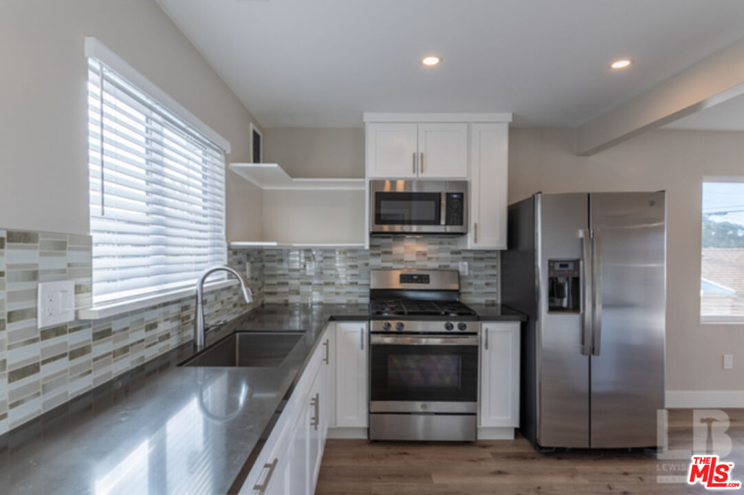 a kitchen with granite countertop a sink stainless steel appliances and window