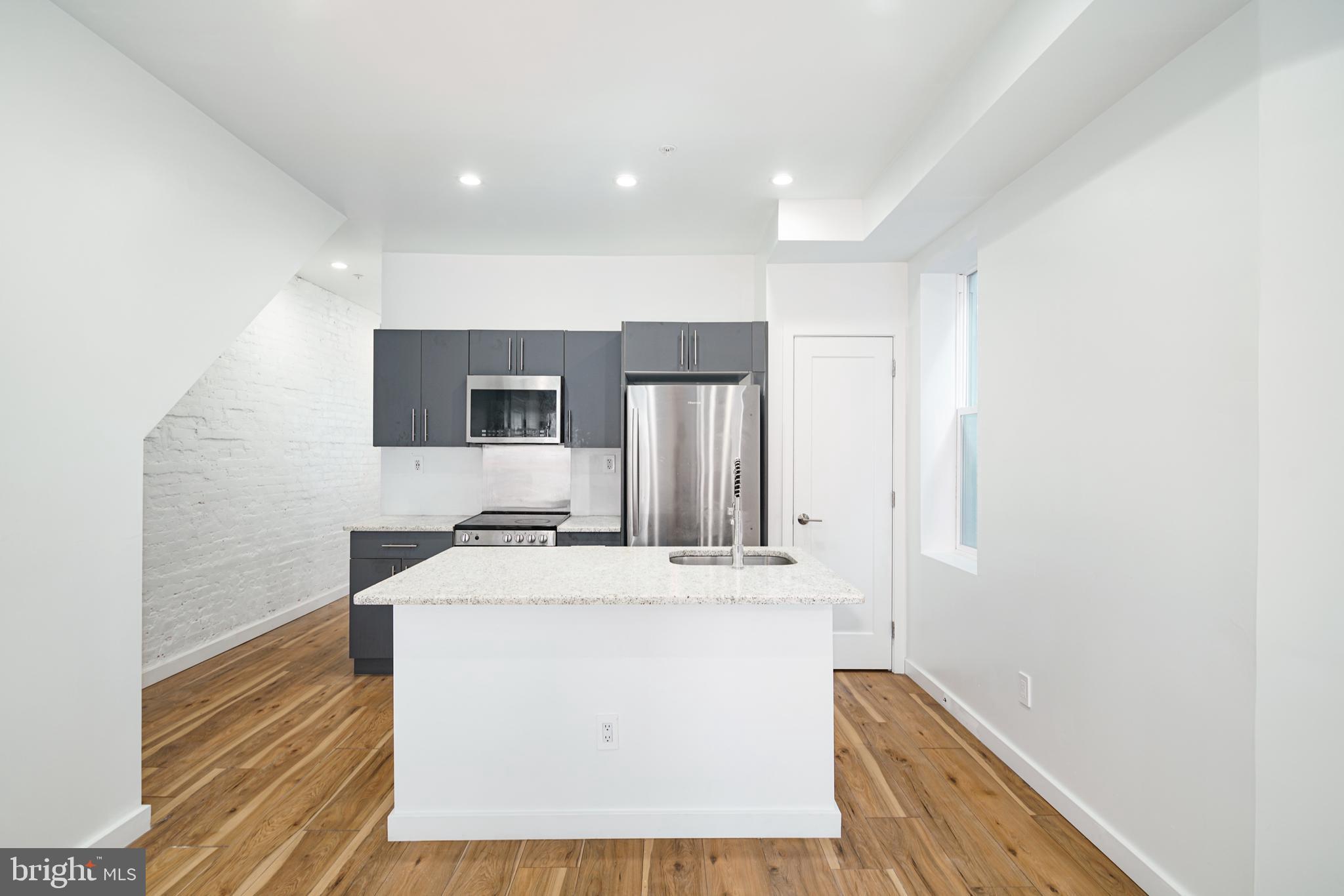 a kitchen with stainless steel appliances granite countertop a sink a stove and a refrigerator