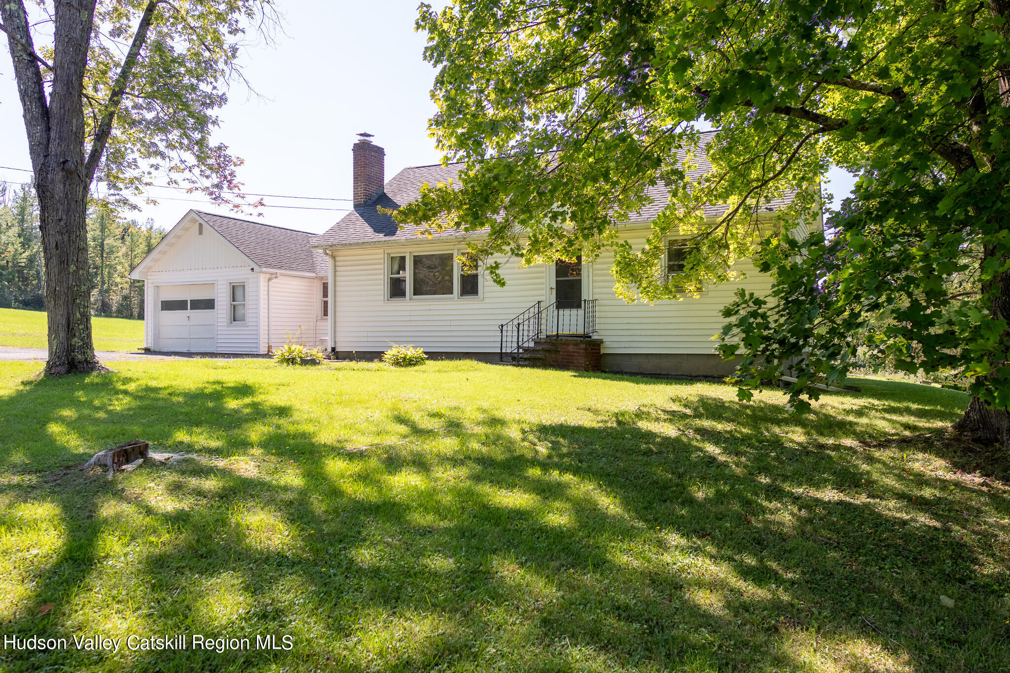 a front view of a house with a yard and trees