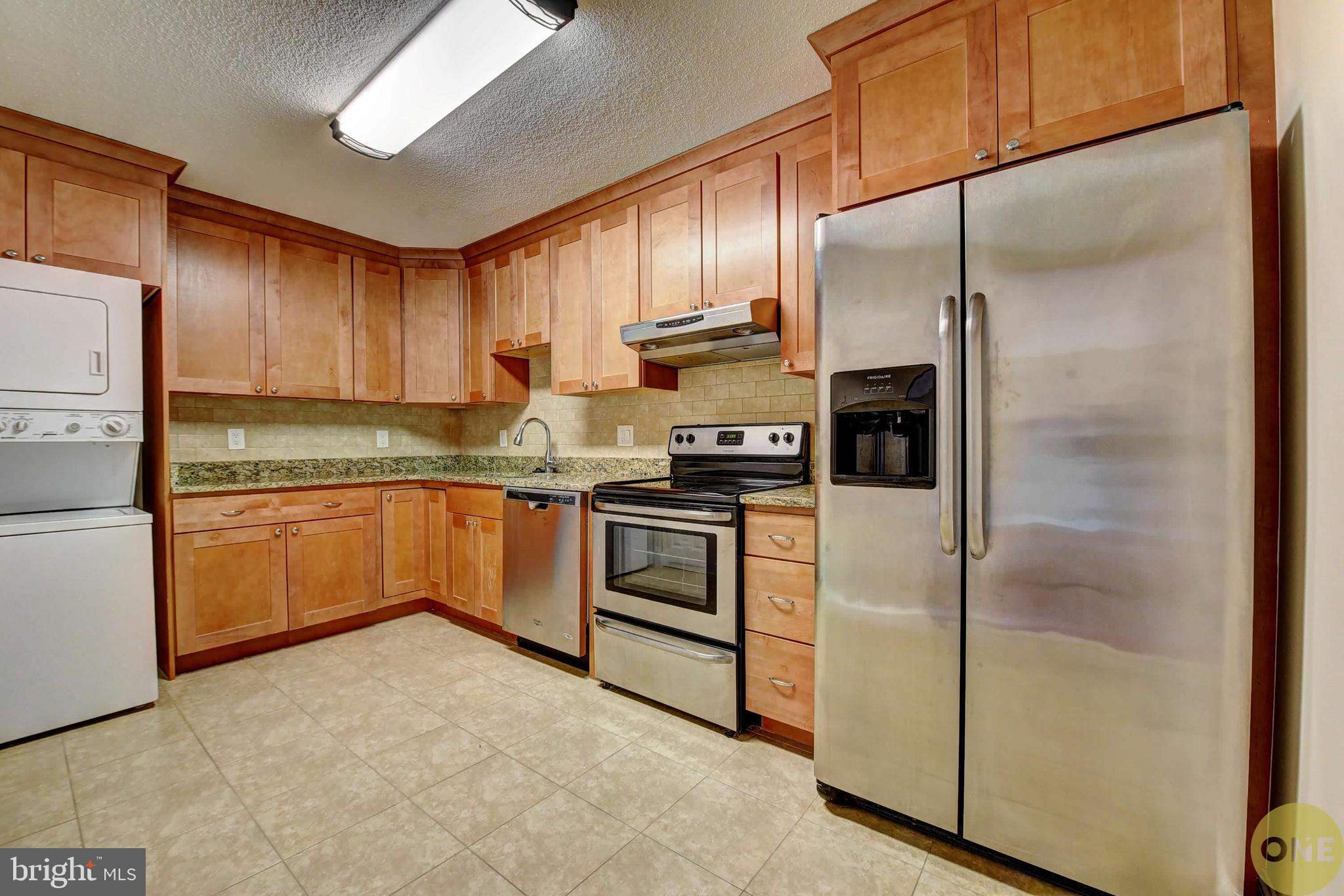 a kitchen with stainless steel appliances granite countertop a refrigerator a sink and white cabinets