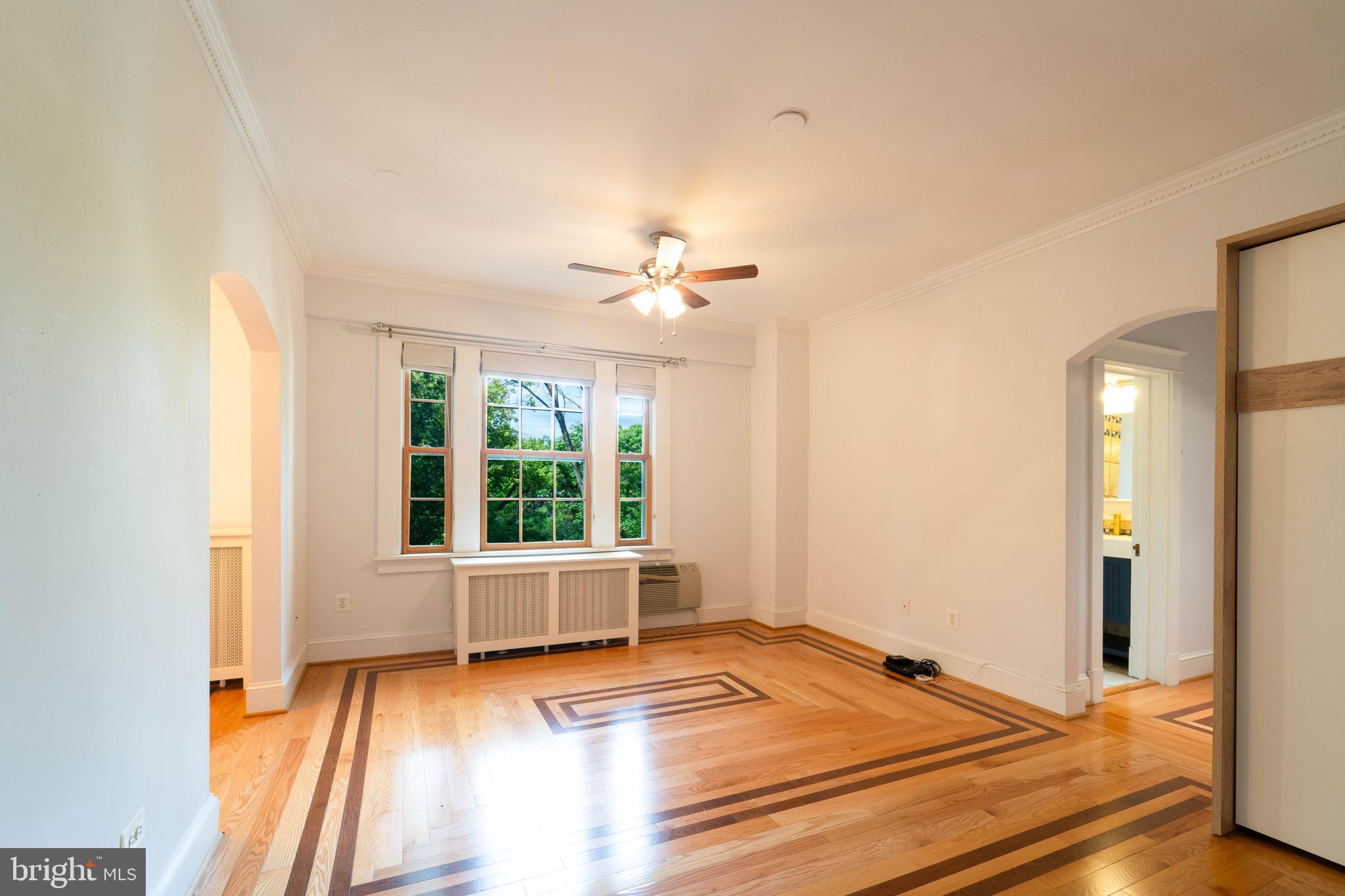 a view of an empty room with a window and wooden floor