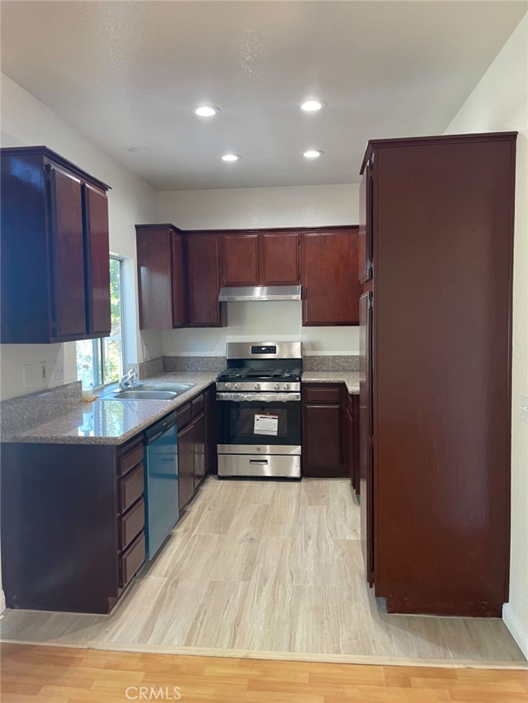 a kitchen with granite countertop wooden cabinets and a stove top oven