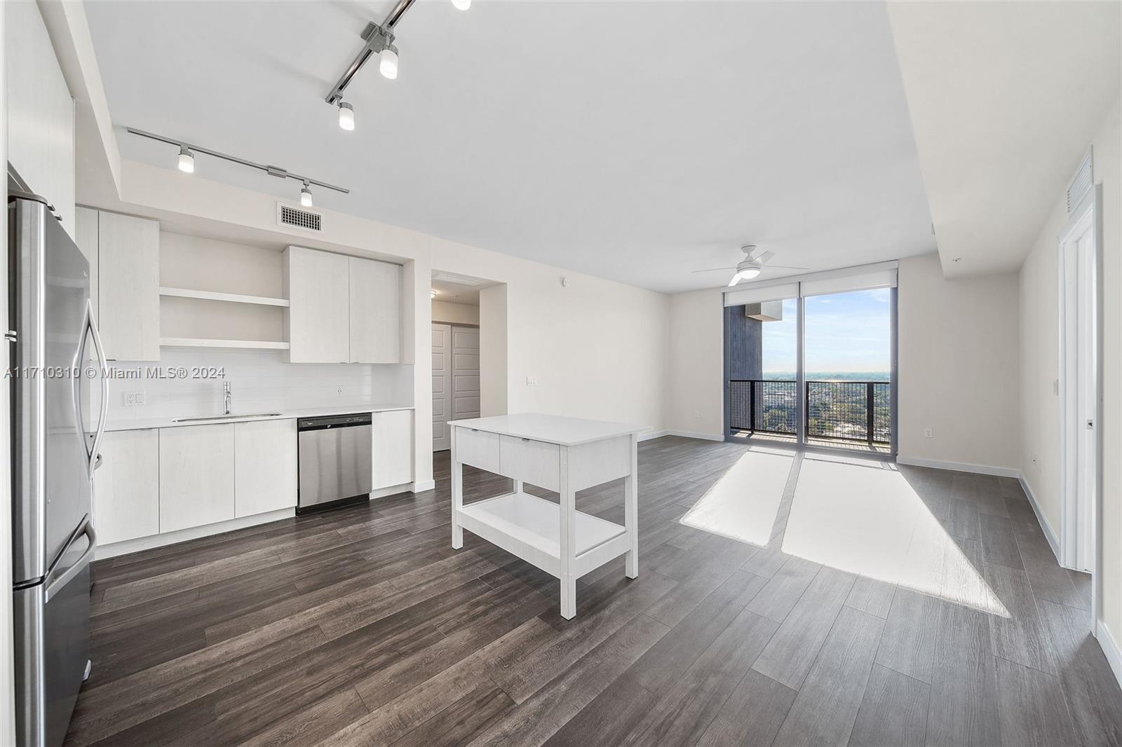 a living room with stainless steel appliances furniture and a kitchen view