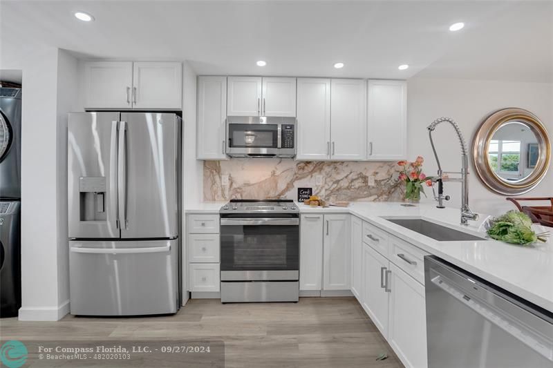 a kitchen with a refrigerator sink and a stove with wooden floor