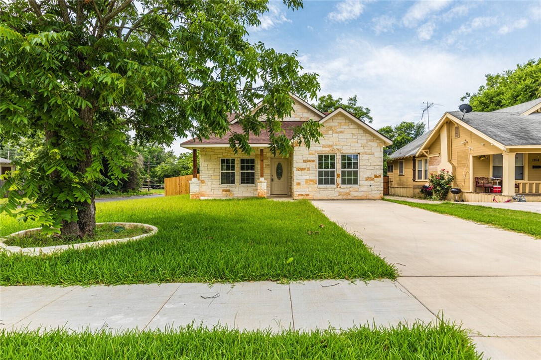 a front view of a house with a yard and trees