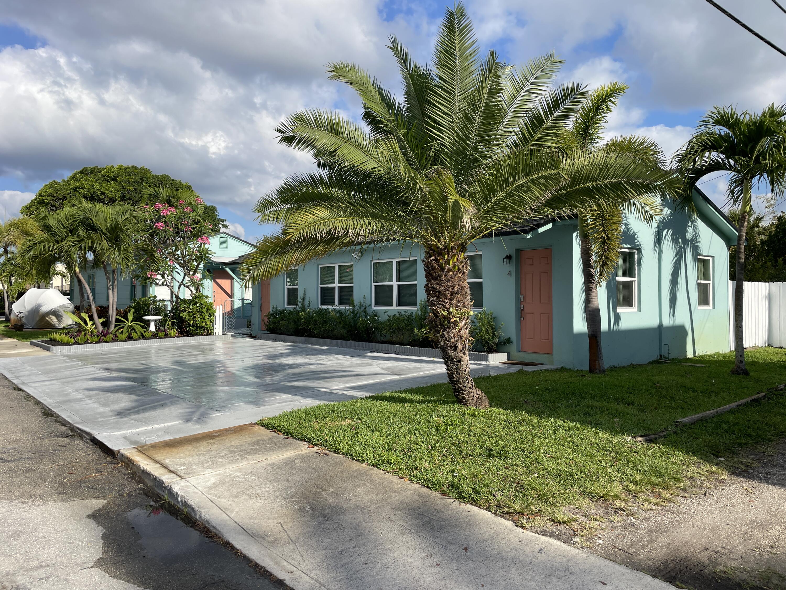 a front view of a house with a yard and palm trees