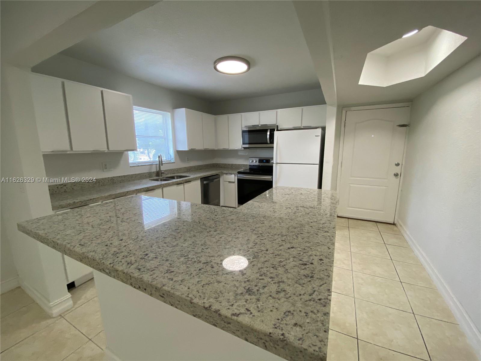 a kitchen with kitchen island granite countertop a sink a counter top space and cabinets