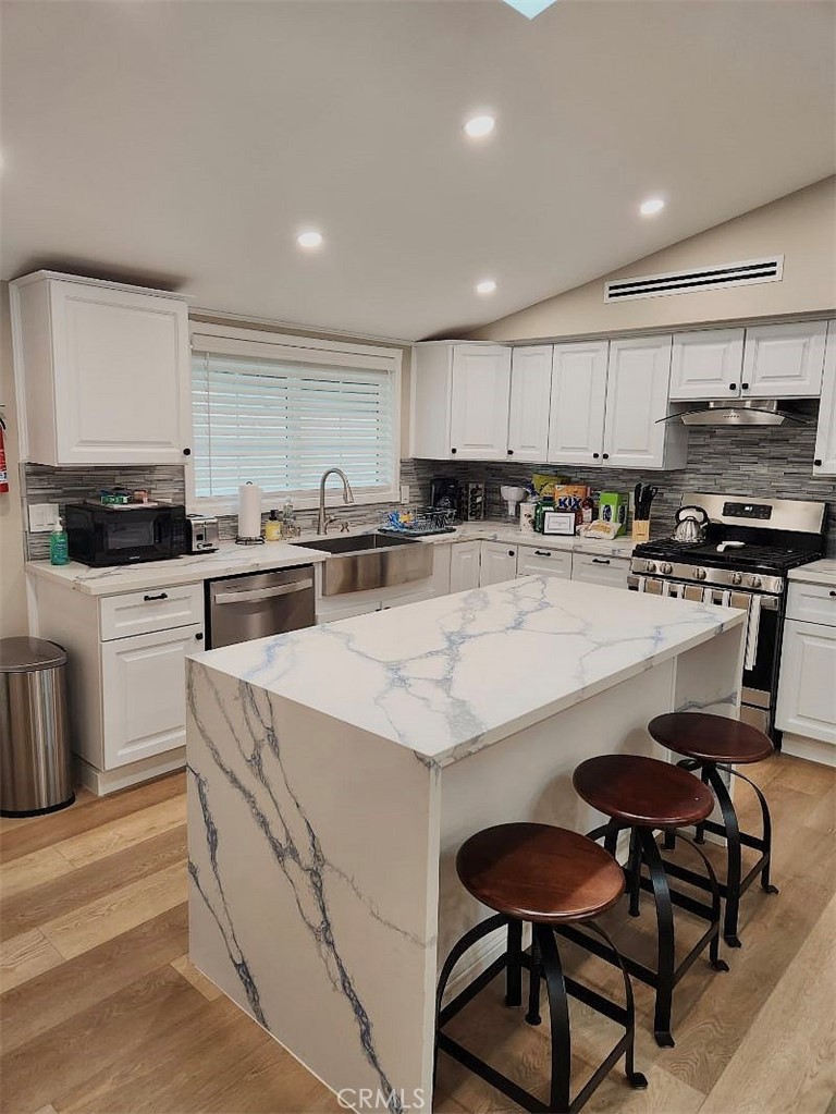 a kitchen with stainless steel appliances kitchen island granite countertop a table chairs sink and cabinets