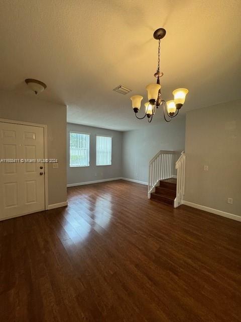 a view of a room with wooden floor chandelier and windows