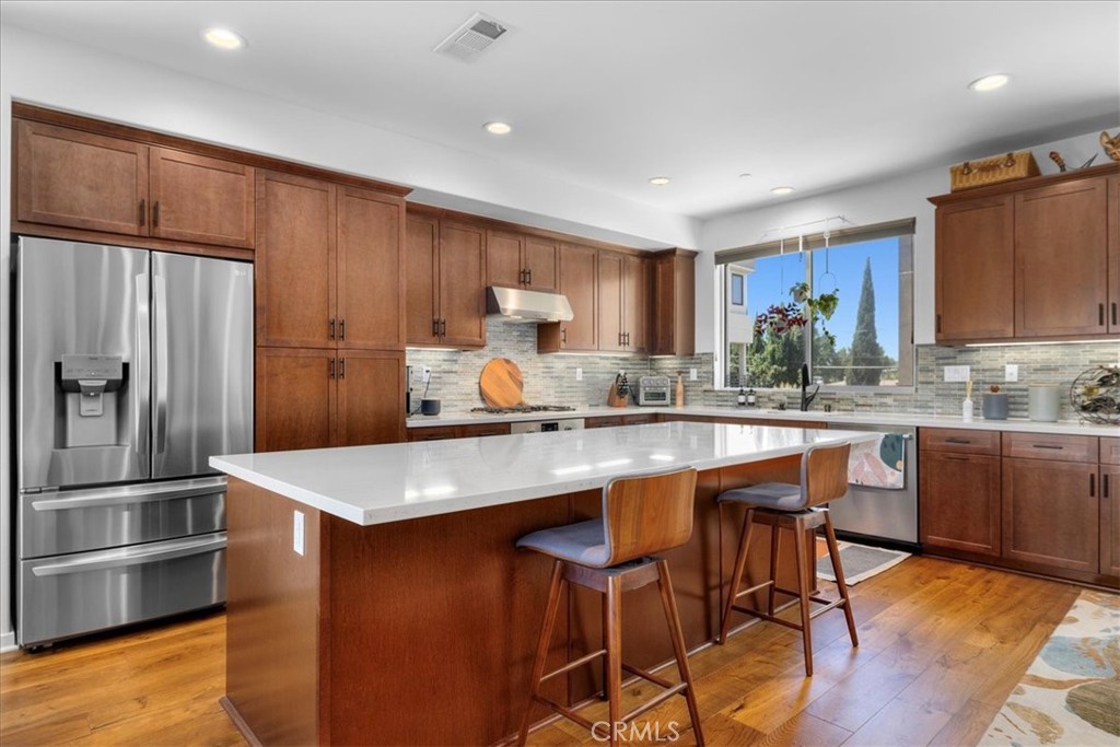 a kitchen with stainless steel appliances granite countertop a sink refrigerator and cabinets