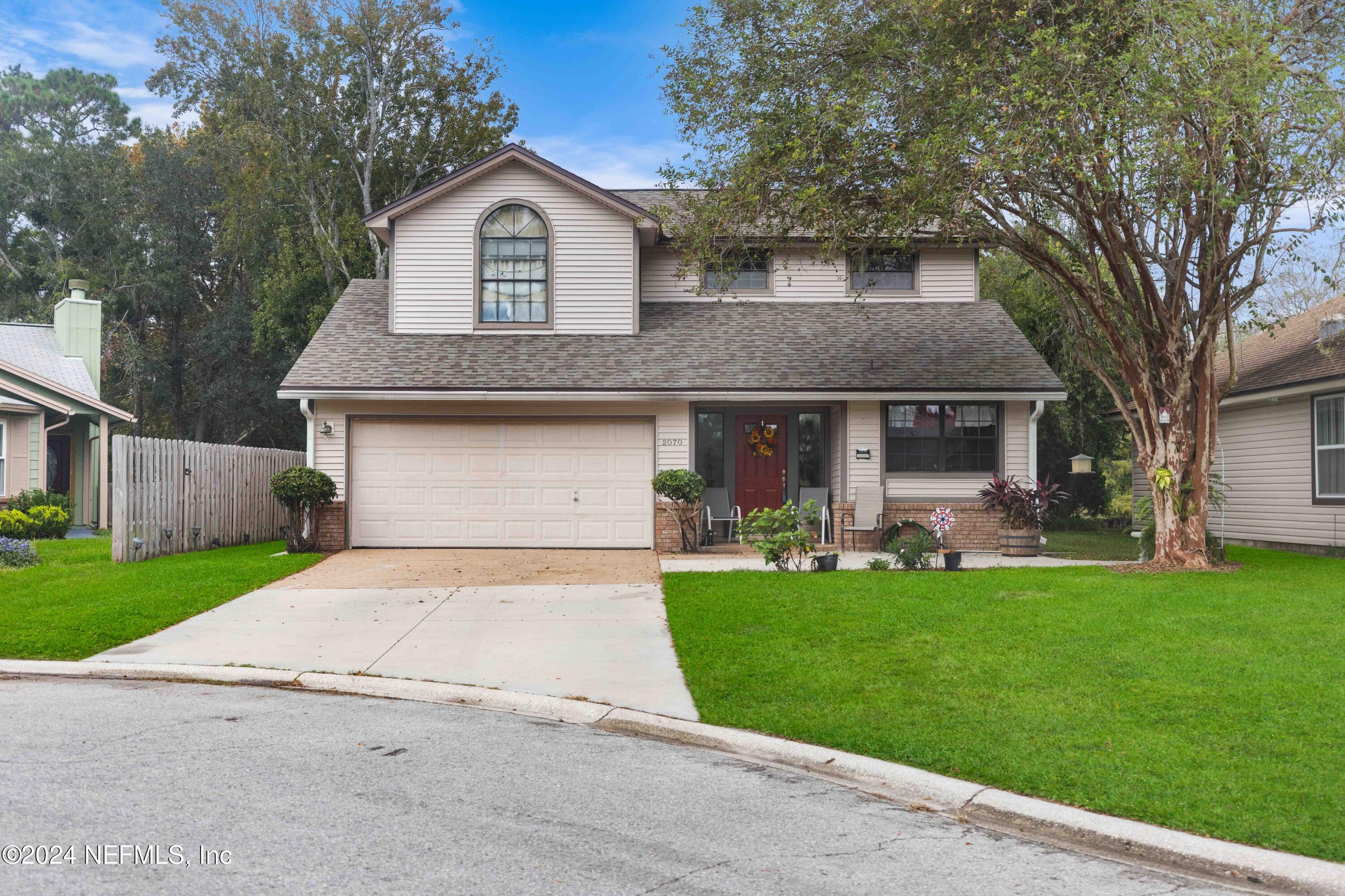 a front view of a house with a garden and trees