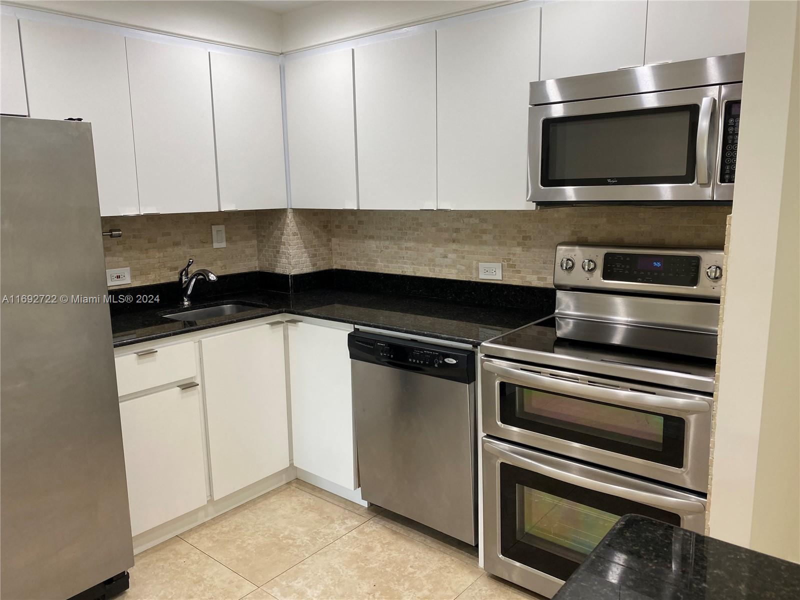 a kitchen with granite countertop a stove and a microwave