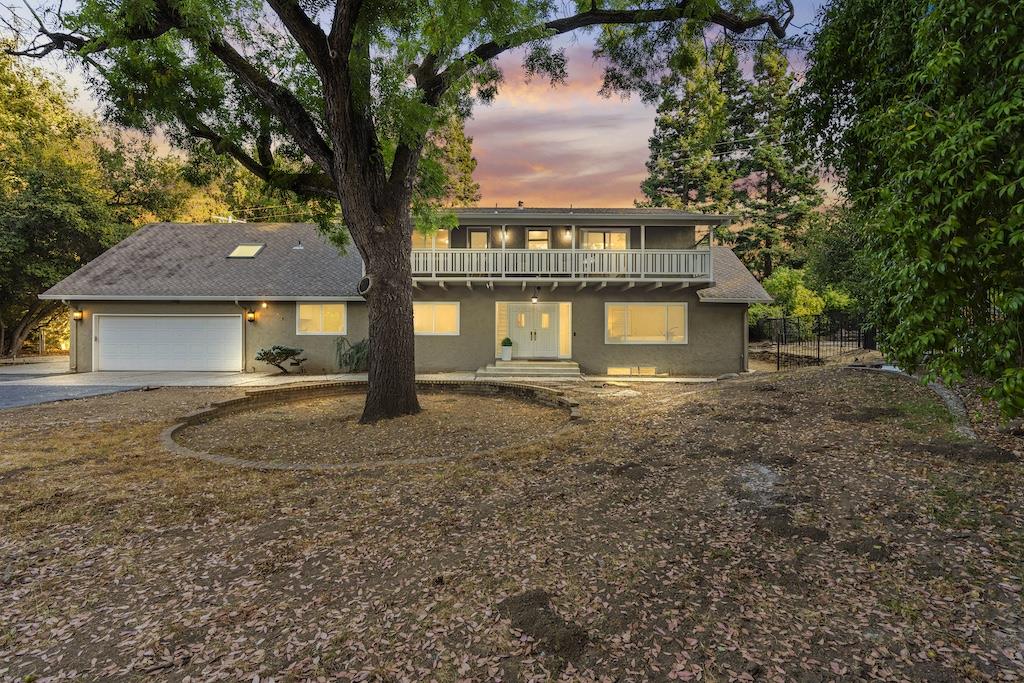 a front view of a house with a yard and large trees