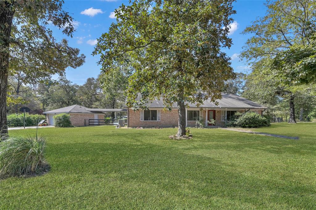 a house that is sitting in the grass with large trees