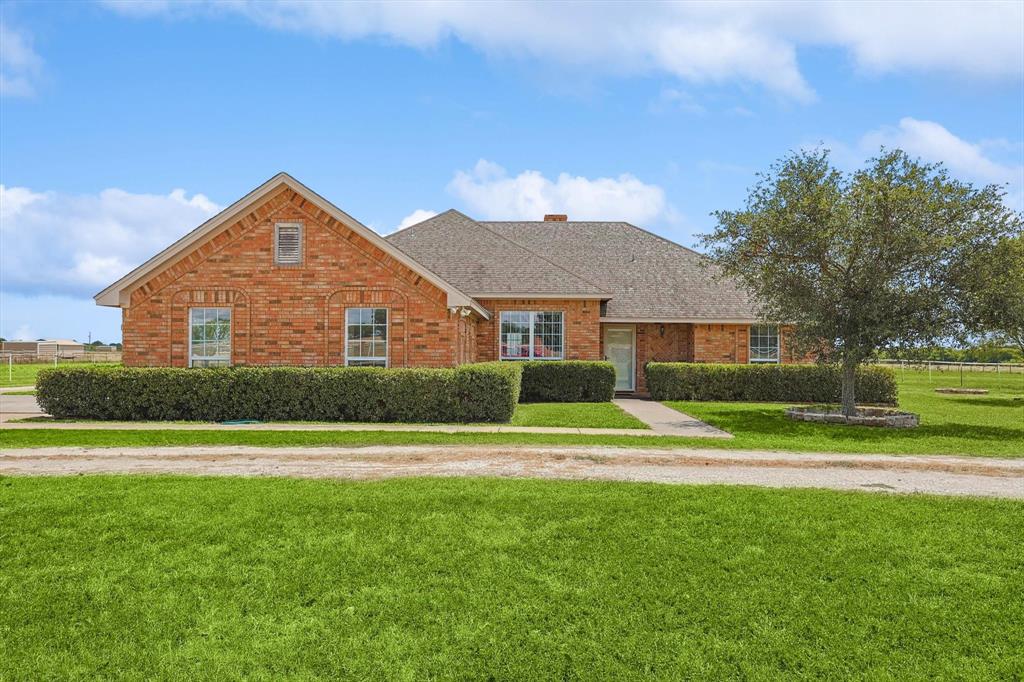 a view of big house in front of a big yard with large trees