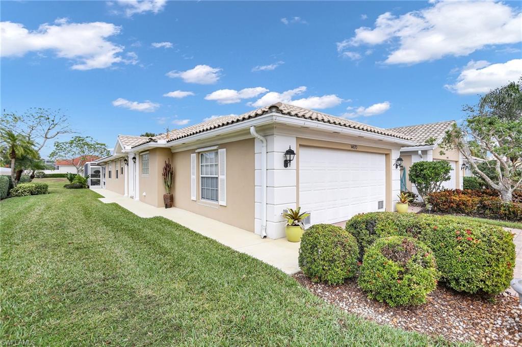 View of side of property featuring a garage and a lawn