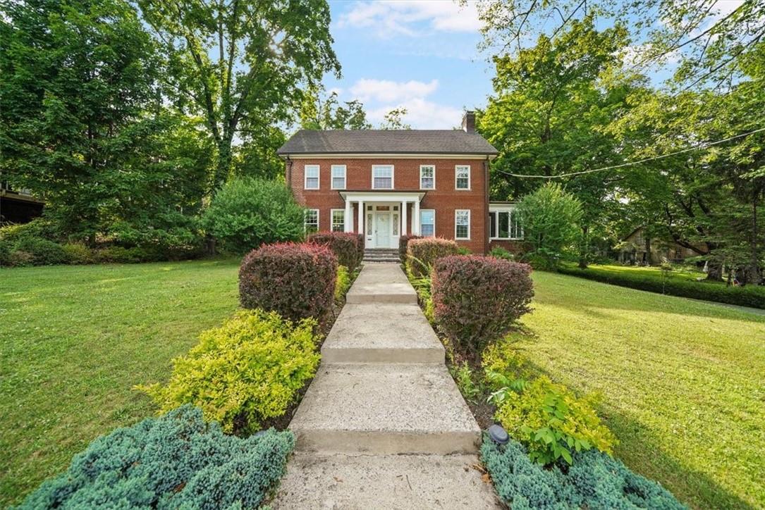 Colonial-style house with beautifully landscaped walkway leading up to the main entrance