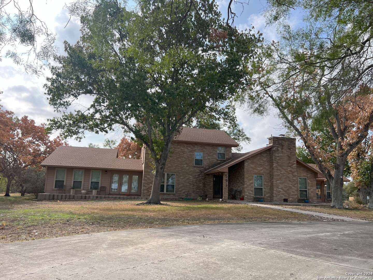 a front view of a house with a garden and trees