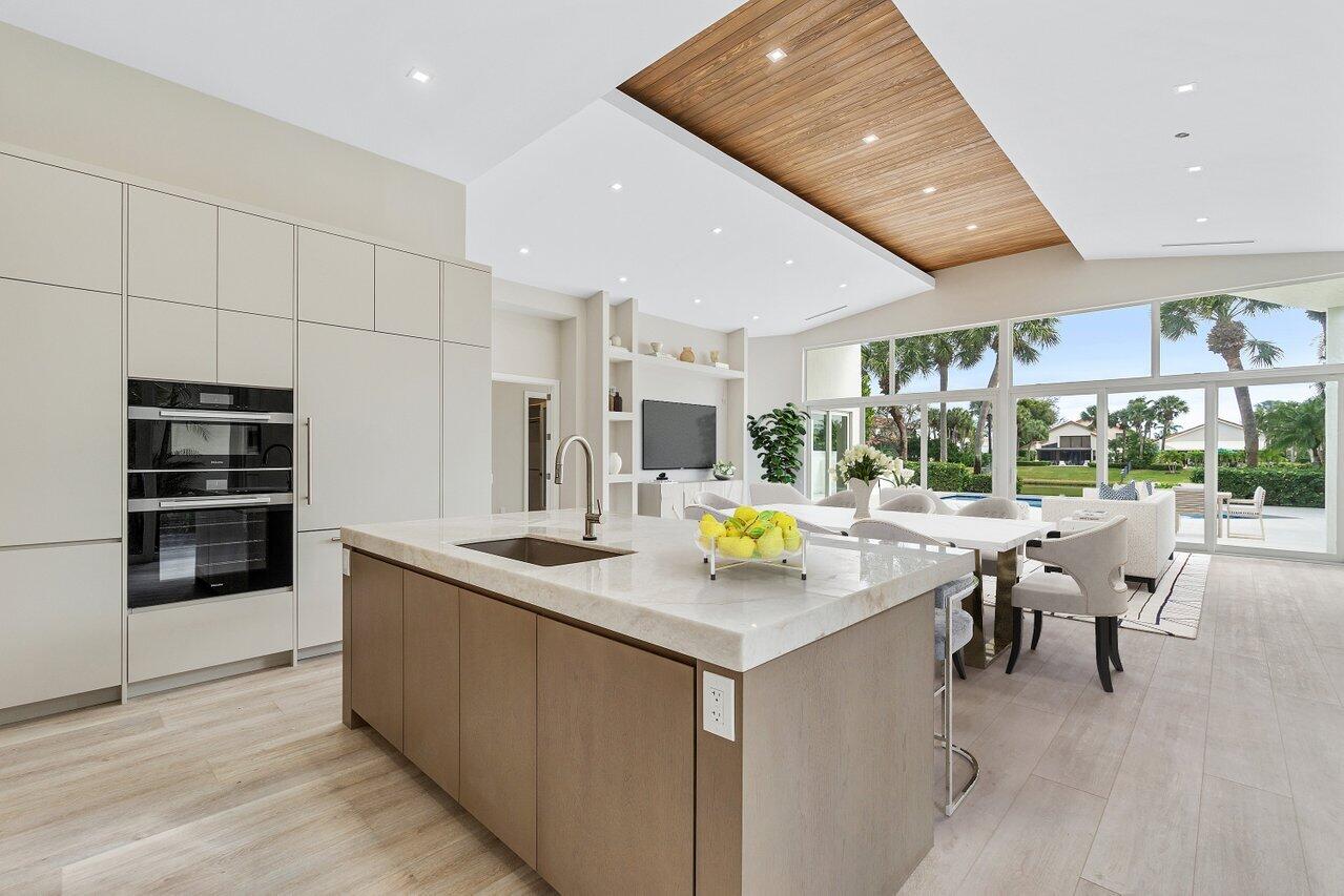 a kitchen with a sink a counter top space stainless steel appliances and a living room view